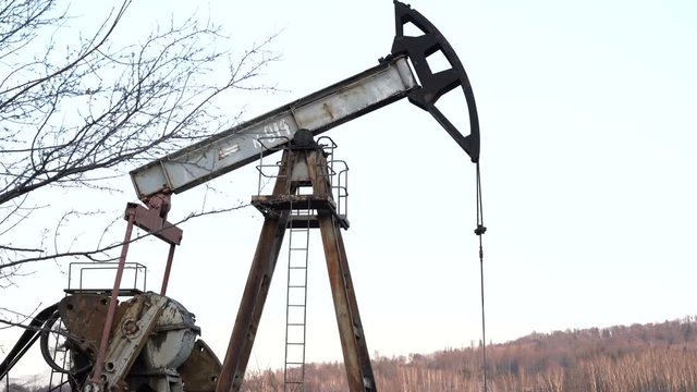 Industrial oil pump jack pumping crude oil for fossil fuel energy with drilling rig in oil field.