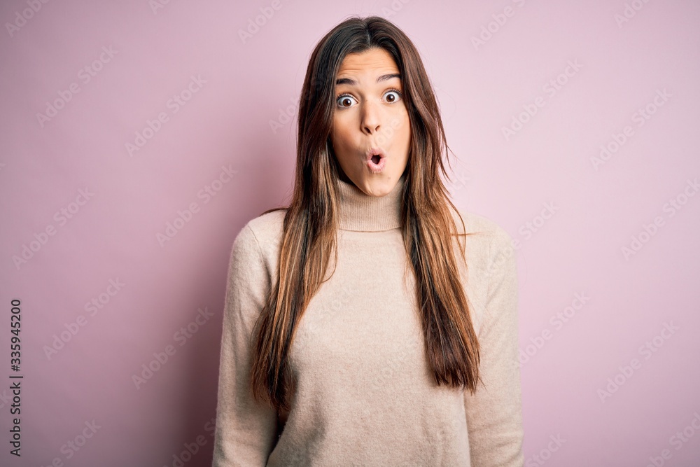 Poster Young beautiful girl wearing casual turtleneck sweater standing over isolated pink background afraid and shocked with surprise expression, fear and excited face.