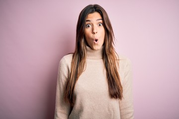 Obraz premium Young beautiful girl wearing casual turtleneck sweater standing over isolated pink background afraid and shocked with surprise expression, fear and excited face.