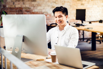 Joyful young man using modern computer at work