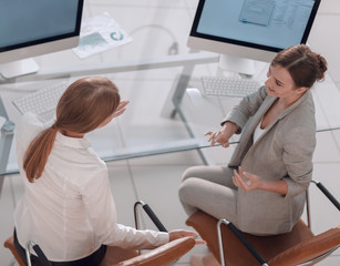 Obraz premium view from the top rear.business woman talking with a colleague sitting near the desktop
