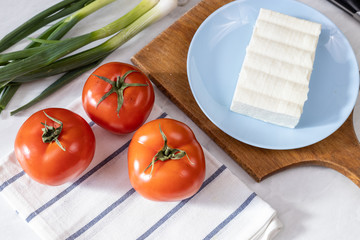 Fresh vegetables tomato and young onions with white cheese on the table