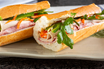A closeup view of a ham and pate banh mi Vietnamese Sandwich, in a restaurant or kitchen setting.