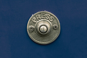 Old fashioned traditional style rustic heavy cast metal doorbell button on a seamless deep blue...