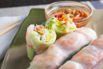 A closeup view of several spring rolls with some cut in half showing the inside contents, in a restaurant or kitchen setting.