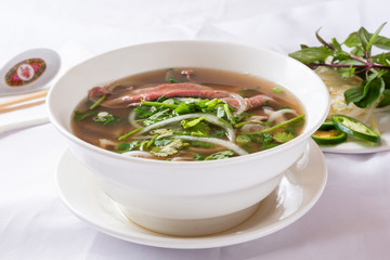 A view of a bowl of pho, in a restaurant or kitchen setting.