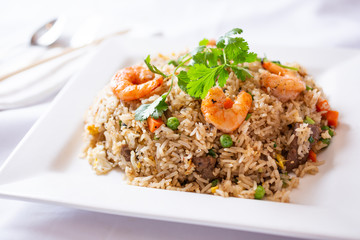 A view of a plate of fried rice, in a restaurant or kitchen setting.