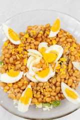 Cooked beans with rice salad served in the bowl decorated with eggs