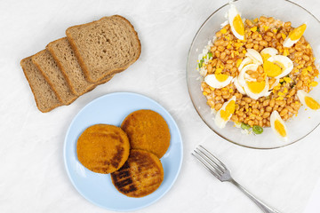 Cooked beans salad with fishcakes and bread served on the table