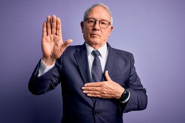 Grey haired senior business man wearing glasses and elegant suit and tie over purple background...