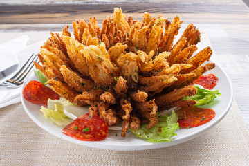 A view of a decorated onion flower appetizer plate, in a restaurant or kitchen setting.