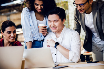 Multiracial young people using laptop and smiling