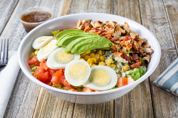A view of a bowl of cobb salad, in a restaurant or kitchen setting.