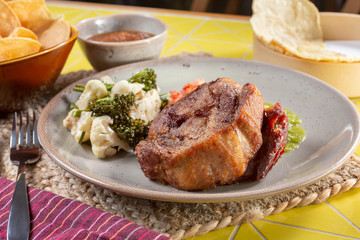 A view of a plate of Mexican carnitas, in a restaurant or kitchen setting.