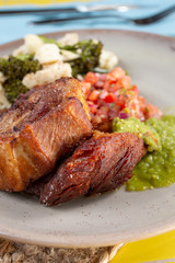 A closeup view of a plate of Mexican carnitas, in a restaurant or kitchen setting.