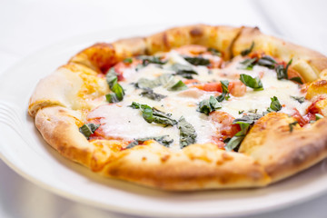 A closeup view of a Margherita pizza pie, in a restaurant or kitchen setting.