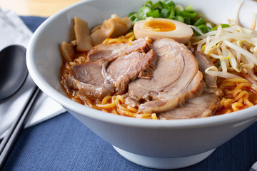 A closeup view of a bowl of spicy miso ramen, in a restaurant or kitchen setting.