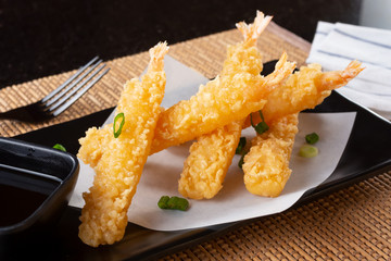 A closeup view of an appetizer plate of tempura shrimp, in a restaurant or kitchen setting.