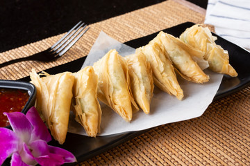 A view of an appetizer plate of spanakopita, in a restaurant or kitchen setting.