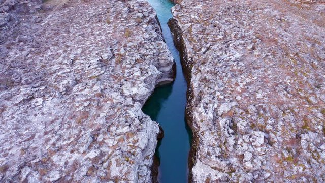 Narrow mountain river flowing through desolate rocky landscape. Stream bed cut deep into stones. Upstream of Cijevna (Cem) in Montenegro. Aerial footage.
