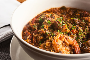 A closeup view of a bowl of jambalaya, in a restaurant or kitchen setting.