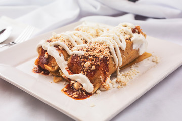 A view of a plate of styled tamales, in a restaurant or kitchen setting.