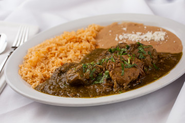 A view of a plate of Mexican chile verde, in a restaurant or kitchen setting.