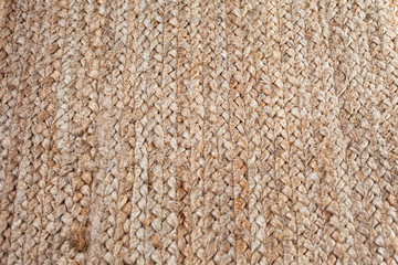 A background and texture of a woven burlap straw placemat, shot at a slight angle. 