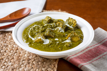 A view of a plate of Indian palak paneer, in a restaurant or kitchen setting.