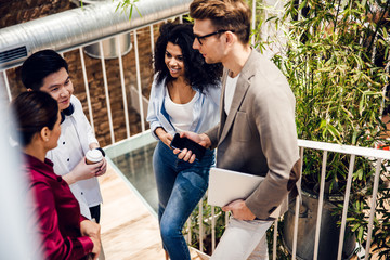 Multiracial young people chatting and laughing during coffee break