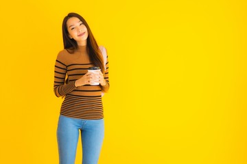 Portrait beautiful young asian woman with bagpack and coffee cup in her hand on yellow background