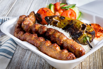 A view of a combination plate of Persian kabab koobideh, in a restaurant or kitchen setting.