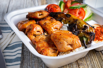 A view of a combo plate featuring Mediterranean chicken thighs, in a restaurant or kitchen setting.