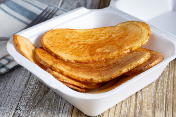 A view of a container of Mediterranean style deep fried potato slices, in a restaurant or kitchen setting.