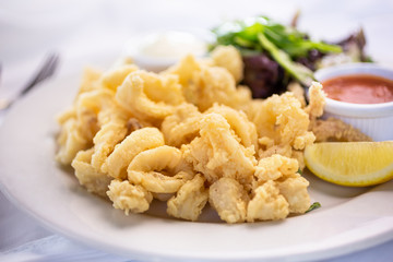 A closeup view of a plate of calamari fritti, in a restaurant or kitchen setting.