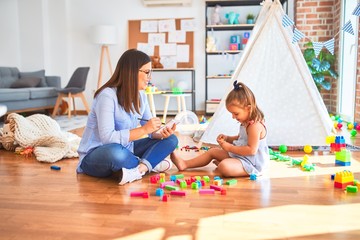 Young therapist woman speaking and treating child, counselor and behaviour correction at pedagogue payroom taking notes on clipboard