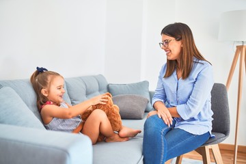 Young therapist woman speaking and treating child, counselor and behaviour correction at pedagogue payroom playing with stuffed animal