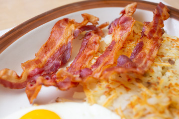 A closeup view of bacon strips on a plate, in a restaurant or kitchen setting.