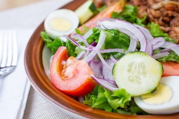 A closeup view of a garden salad, in a restaurant or kitchen setting.