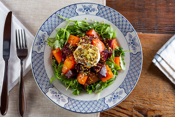 A top down view of a salad with arugula and beets, in a restaurant or kitchen setting.