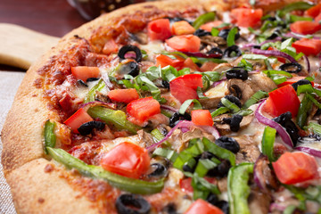 A closeup view of a veggie pizza pie, in a restaurant or kitchen setting.