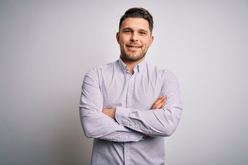 Young business man with blue eyes standing over isolated background happy face smiling with crossed arms looking at the camera. Positive person.