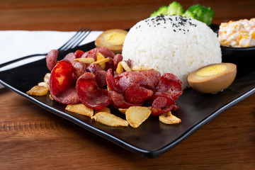 A view of a plate of Chinese sausage and roasted garlic, in a restaurant or kitchen setting.