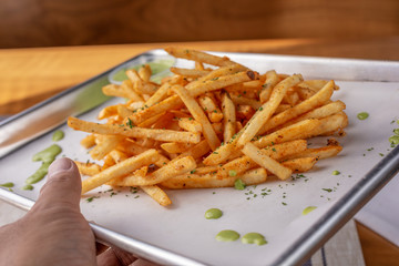 A closeup view of a tray of cajun style french fries in a restaurant or kitchen setting.