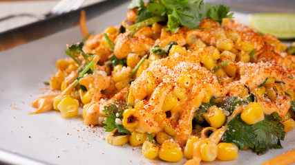 A view of a tray of deconstructed Mexican elote street food, in a restaurant or kitchen setting.