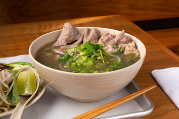 A view of a pho soup bowl with slice of beef, in a restaurant or kitchen setting.