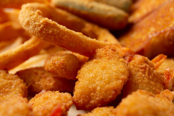 A closeup view of several varieties of deep fried appetizers, featuring Texas toast, onion rings, and zucchini sticks.