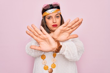 Young hispanic hippie woman wearing fashion boho style and sunglasses over pink background Rejection expression crossing arms and palms doing negative sign, angry face