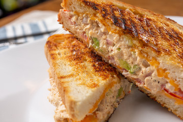 A closeup view of a tuna melt sandwich, in a restaurant or kitchen setting.