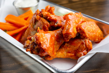 A closeup view of a tray of buffalo wings, in a restaurant or kitchen setting.